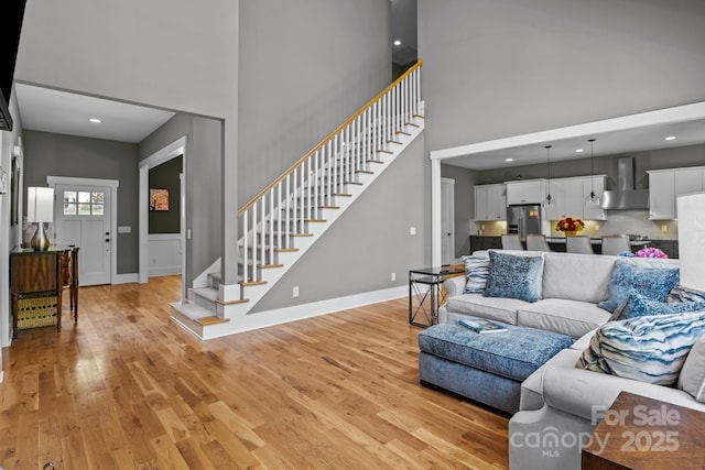 living area featuring stairs, a high ceiling, and light wood-type flooring