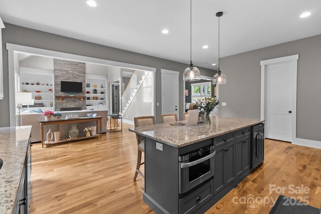 kitchen with recessed lighting, stainless steel oven, a kitchen breakfast bar, and light wood-type flooring