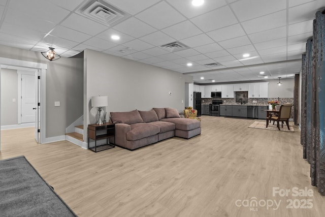 living room with stairway, visible vents, baseboards, and light wood finished floors