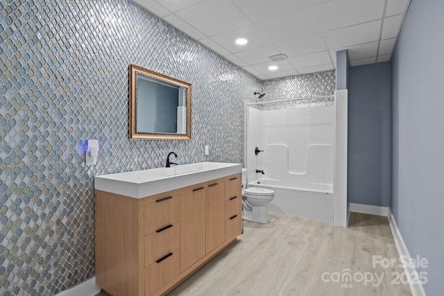 full bath with vanity, wood finished floors, toilet, bathing tub / shower combination, and baseboards