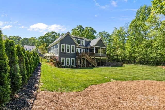 rear view of property featuring stairs, a lawn, a sunroom, and a deck