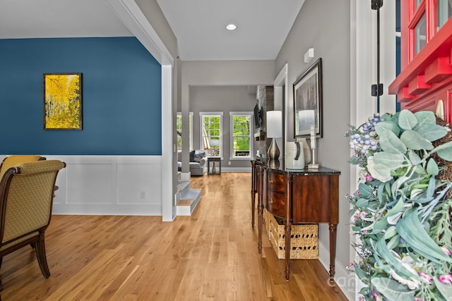 corridor with light wood-style floors, recessed lighting, and a wainscoted wall