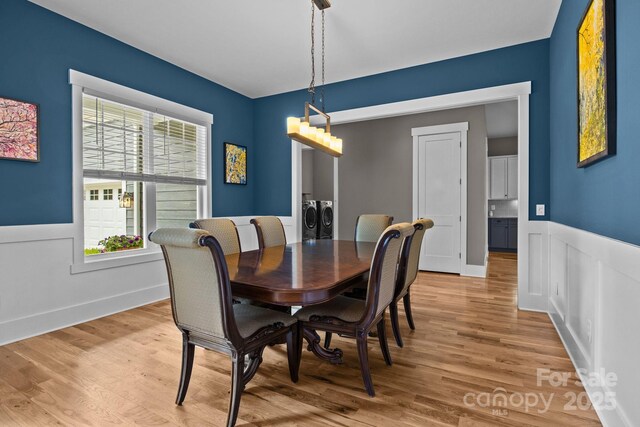 dining room featuring separate washer and dryer, light wood-style floors, and wainscoting