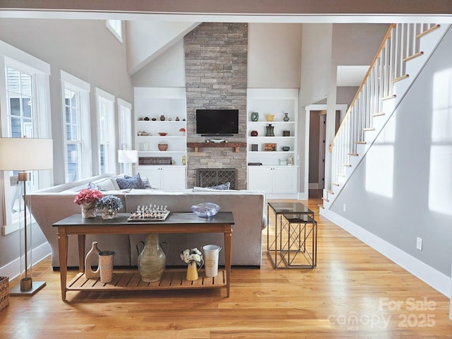 living room featuring high vaulted ceiling, baseboards, and built in shelves