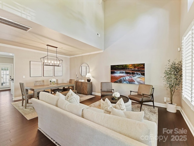 living room with baseboards, visible vents, a wealth of natural light, and dark wood-type flooring