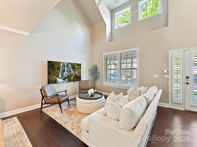 living area featuring dark wood-style floors, a ceiling fan, high vaulted ceiling, and baseboards