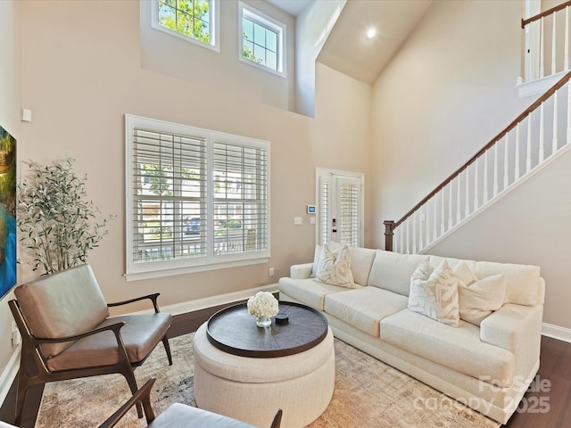 living room featuring baseboards, high vaulted ceiling, and stairway