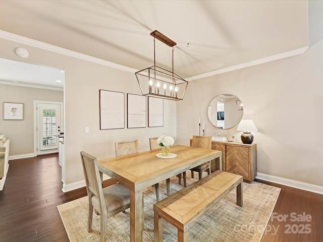 dining room with dark wood-type flooring, crown molding, a notable chandelier, and baseboards