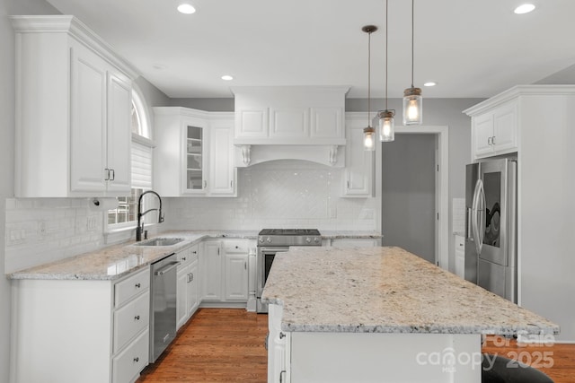 9008 Skipaway Dr, Waxhaw, NC 28173 - kitchen featuring stainless steel appliances, a sink, wood finished floors, a kitchen island, and white cabinetry