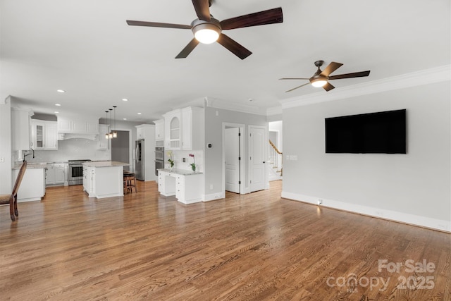 9008 Skipaway Dr, Waxhaw, NC 28173 - unfurnished living room featuring ceiling fan, crown molding, recessed lighting, stairs, and light wood-style floors