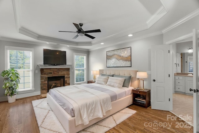 9008 Skipaway Dr, Waxhaw, NC 28173 - bedroom with a tray ceiling, ornamental molding, wood finished floors, a stone fireplace, and a ceiling fan