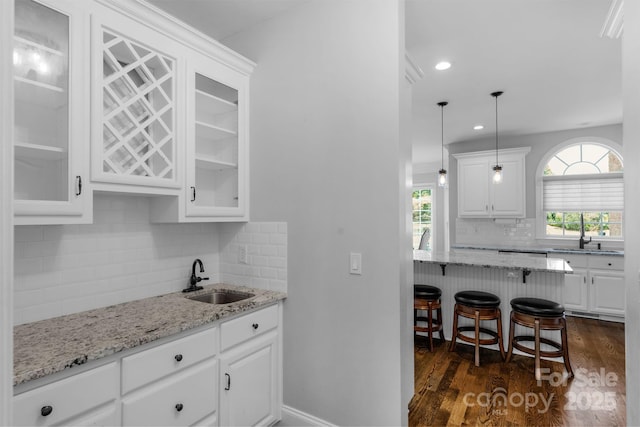 9008 Skipaway Dr, Waxhaw, NC 28173 - kitchen featuring a sink, a kitchen breakfast bar, white cabinets, glass insert cabinets, and recessed lighting