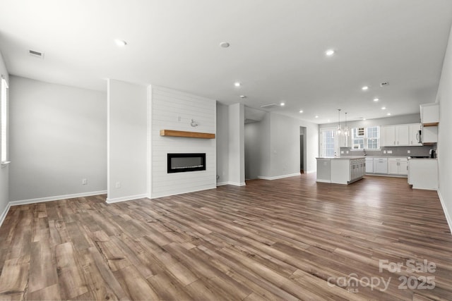 unfurnished living room featuring baseboards, recessed lighting, wood finished floors, and a fireplace