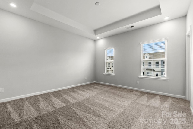 spare room with a tray ceiling, baseboards, and carpet floors