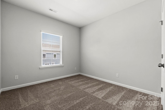 unfurnished room featuring baseboards, dark colored carpet, and visible vents