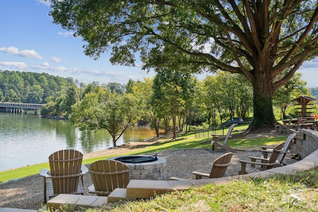 view of community featuring an outdoor fire pit, a lawn, and a water view