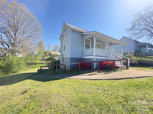 view of front of house with a porch, metal roof, and a front yard