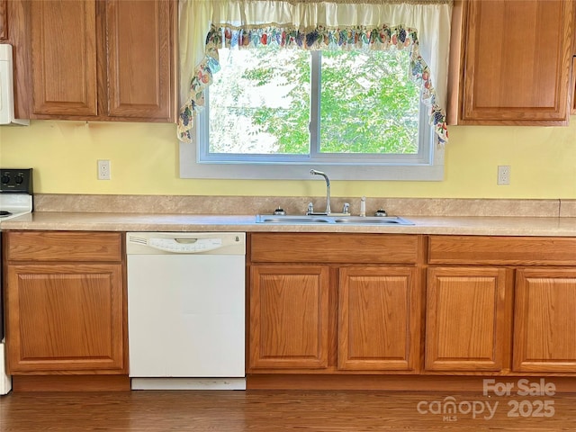 kitchen featuring a sink, light countertops, white appliances, and wood finished floors