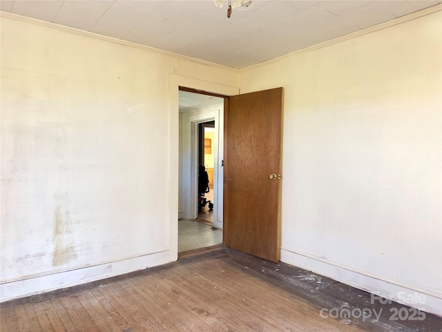 spare room with hardwood / wood-style floors, crown molding, and baseboards