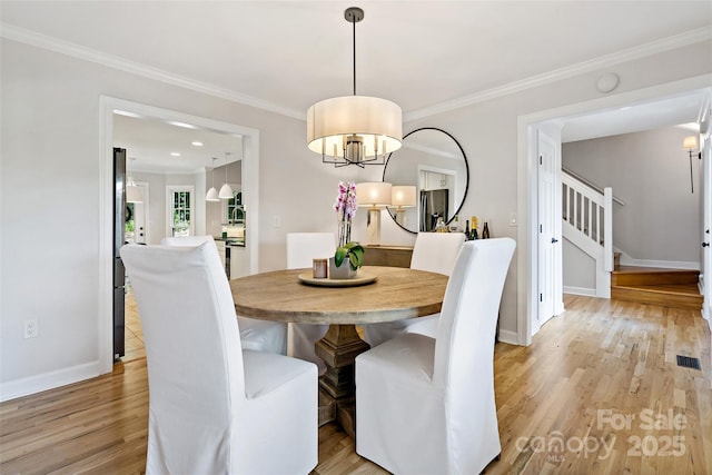 dining room featuring stairs, a notable chandelier, light wood-style flooring, and visible vents