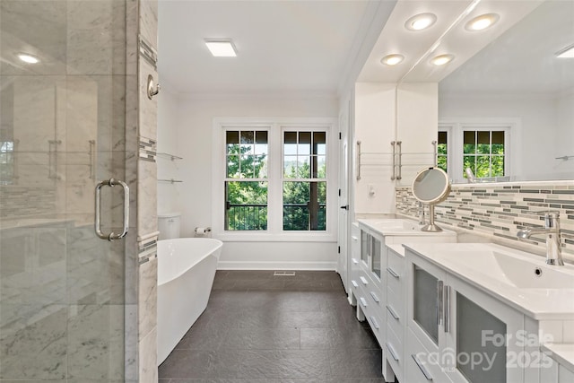 full bathroom with double vanity, crown molding, a freestanding tub, a stall shower, and a sink