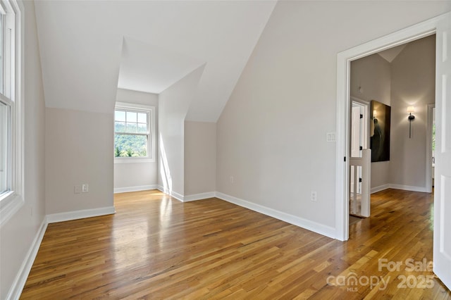 bonus room with baseboards, lofted ceiling, and light wood-type flooring
