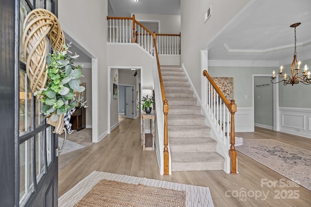 1809 Robbins Meadows Dr, Waxhaw, NC 28173 - foyer entrance featuring stairs, a chandelier, light wood-style floors, ornamental molding, and a towering ceiling