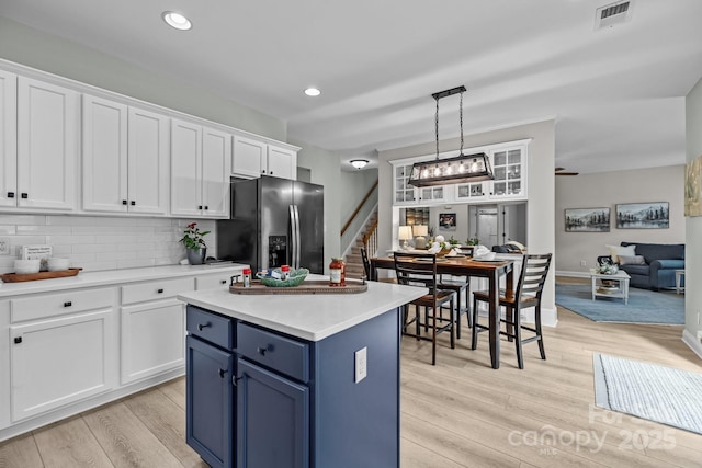 1809 Robbins Meadows Dr, Waxhaw, NC 28173 - kitchen featuring stainless steel fridge with ice dispenser, blue cabinets, white cabinets, light wood-type flooring, and light countertops