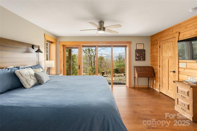 263 Mine Cove Rd, Spruce Pine, NC 28777 - bedroom with baseboards, wooden walls, wood finished floors, a ceiling fan, and access to outside