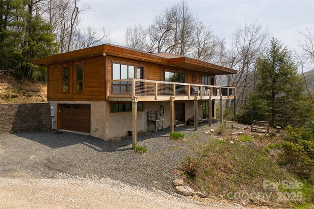 263 Mine Cove Rd, Spruce Pine, NC 28777 - back of property with stucco siding, a deck, gravel driveway, and a garage