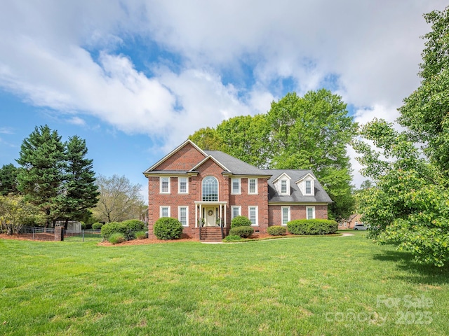 view of front of property with a front yard, brick siding, and fence