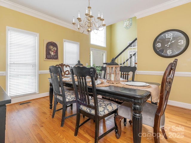 dining area featuring baseboards, a notable chandelier, ornamental molding, stairway, and wood finished floors