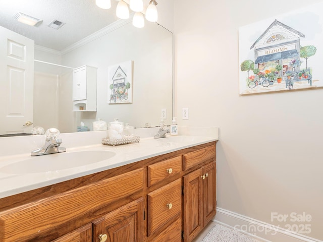 bathroom featuring crown molding, double vanity, a sink, and visible vents