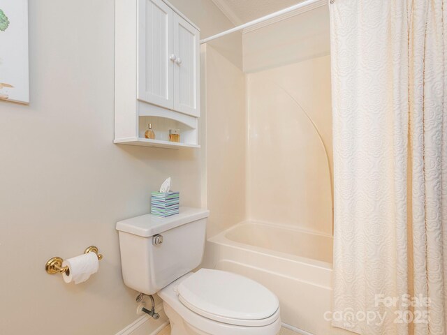 bathroom featuring toilet, shower / tub combo, and baseboards
