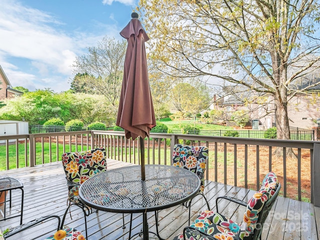 wooden terrace with a storage shed, an outbuilding, a fenced backyard, and outdoor dining area