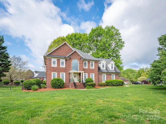 colonial house with brick siding, a front yard, and fence