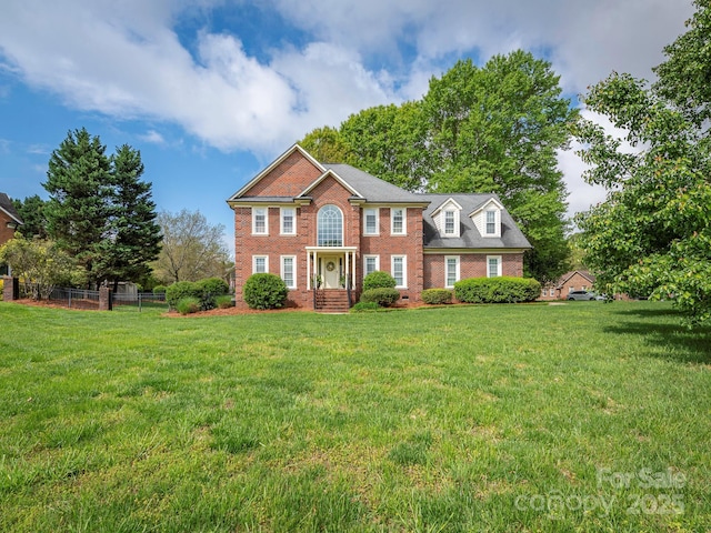 view of front facade featuring brick siding, a front lawn, and fence