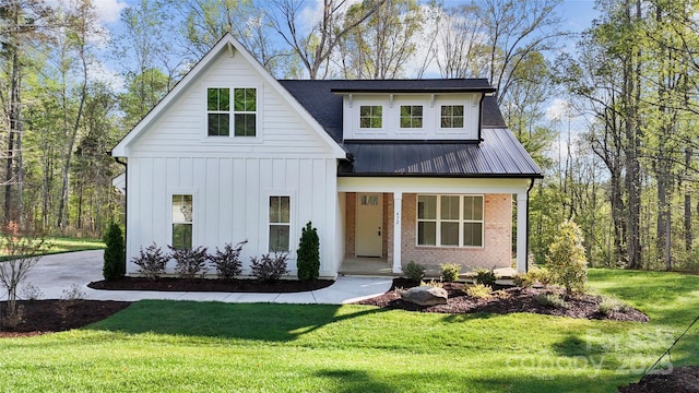 472 Bellingshire Dr, Mount Ulla, NC 28125 - modern farmhouse style home featuring board and batten siding, a porch, metal roof, a front lawn, and brick siding