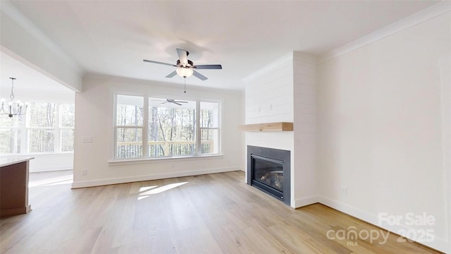 472 Bellingshire Dr, Mount Ulla, NC 28125 - unfurnished living room with baseboards, light wood-type flooring, a glass covered fireplace, and ceiling fan with notable chandelier