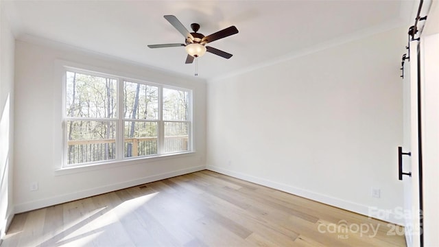 472 Bellingshire Dr, Mount Ulla, NC 28125 - unfurnished room featuring baseboards, a barn door, ornamental molding, a ceiling fan, and wood finished floors