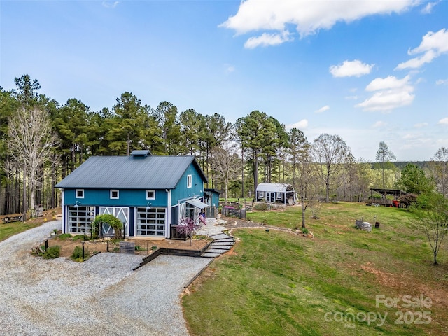 back of property with stairs, driveway, and a lawn