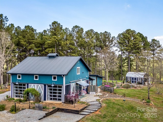 rear view of property featuring metal roof and an outdoor structure