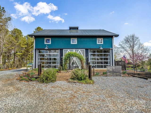 rear view of property with metal roof and fence