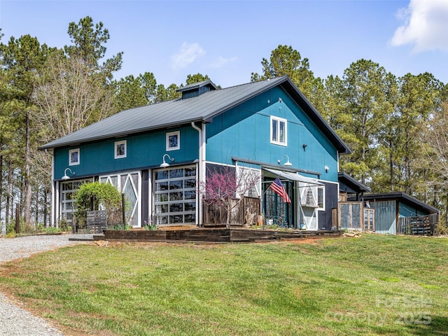 view of front of home with an outbuilding, metal roof, a front yard, and driveway