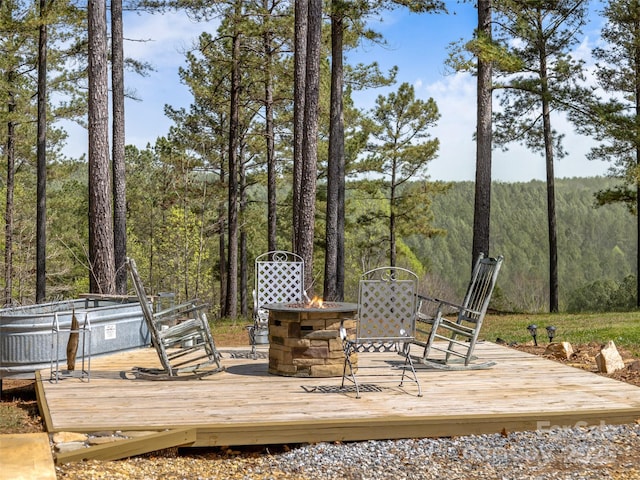 deck with a fire pit and a forest view