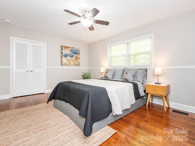 bedroom featuring ceiling fan, a closet, visible vents, wood finished floors, and baseboards