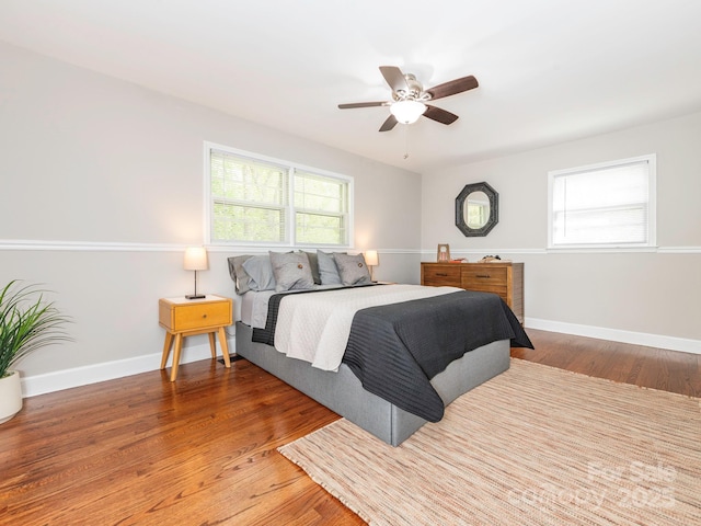 bedroom featuring multiple windows, baseboards, and wood finished floors