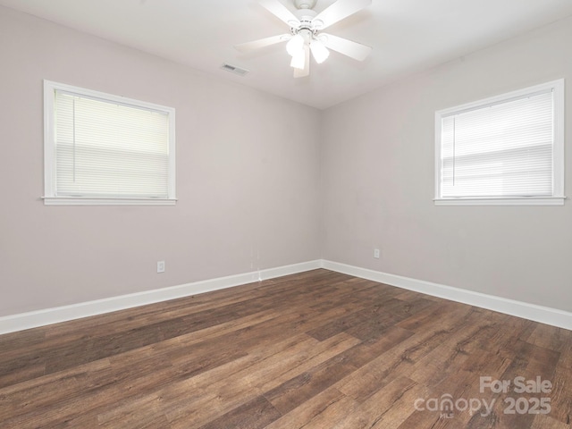 unfurnished room with dark wood-type flooring, visible vents, baseboards, and a ceiling fan