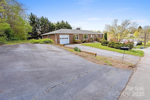 ranch-style home featuring a front lawn, brick siding, an attached garage, a chimney, and driveway