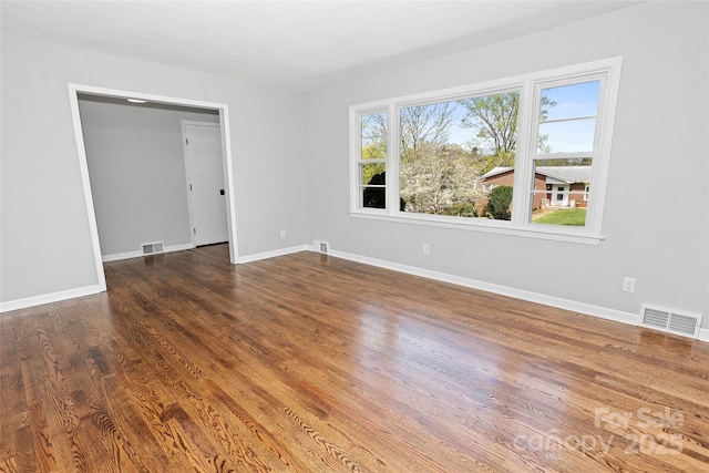 empty room featuring visible vents, baseboards, and wood finished floors